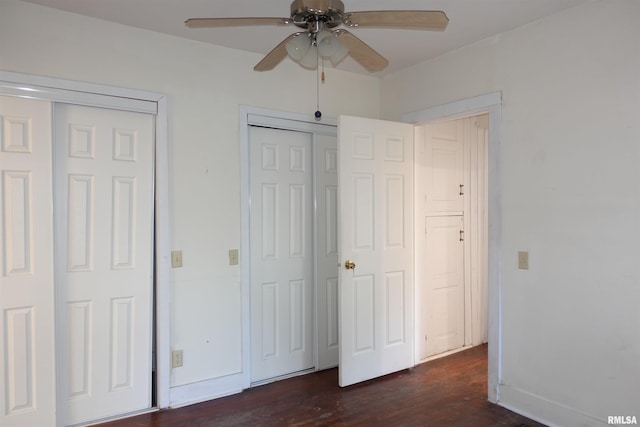 unfurnished bedroom featuring ceiling fan, multiple closets, and dark hardwood / wood-style flooring