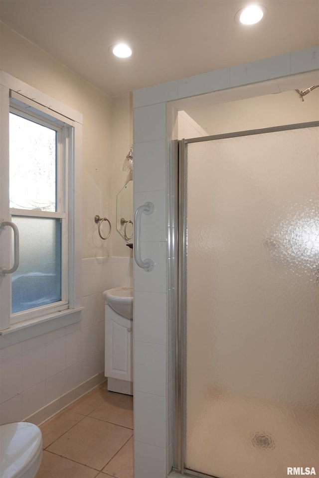 bathroom with vanity, tile patterned flooring, tile walls, and a shower with door