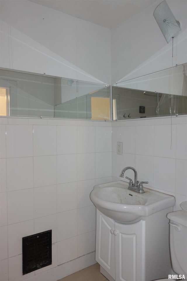 bathroom with toilet, tile walls, backsplash, and vanity