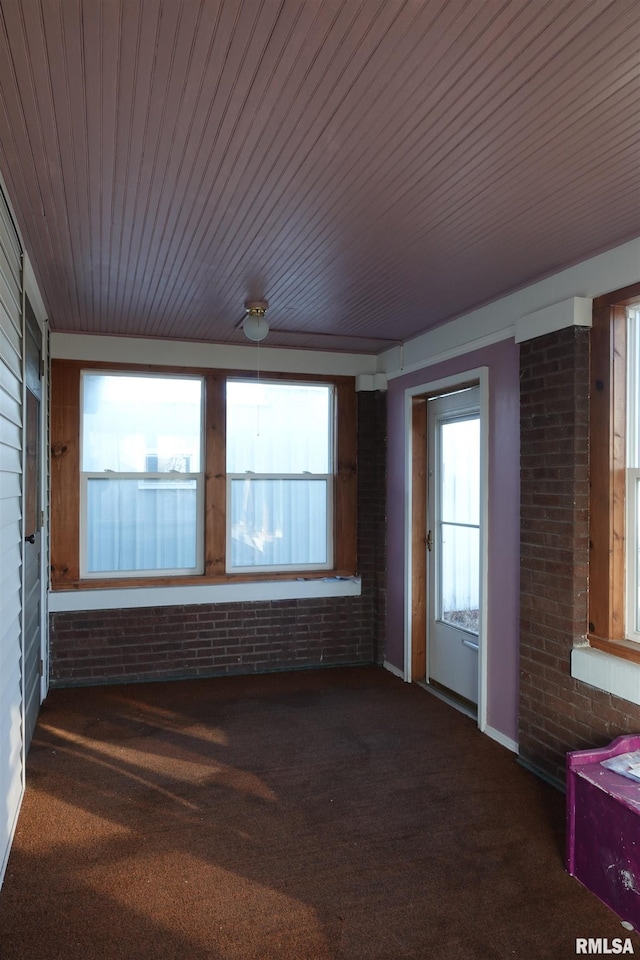 interior space featuring dark colored carpet and brick wall