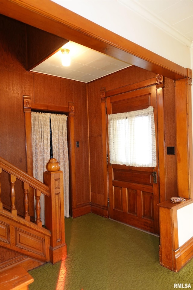 entrance foyer featuring crown molding, dark carpet, and wooden walls