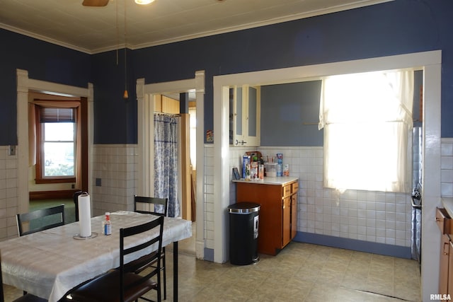 dining room featuring ceiling fan, tile walls, plenty of natural light, and ornamental molding