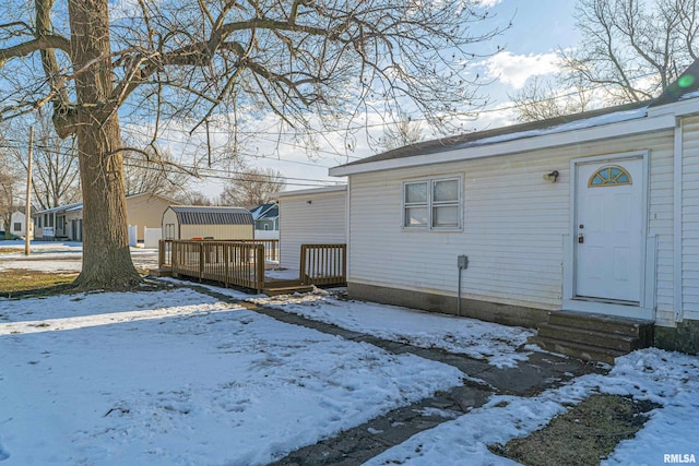 snow covered rear of property with a deck