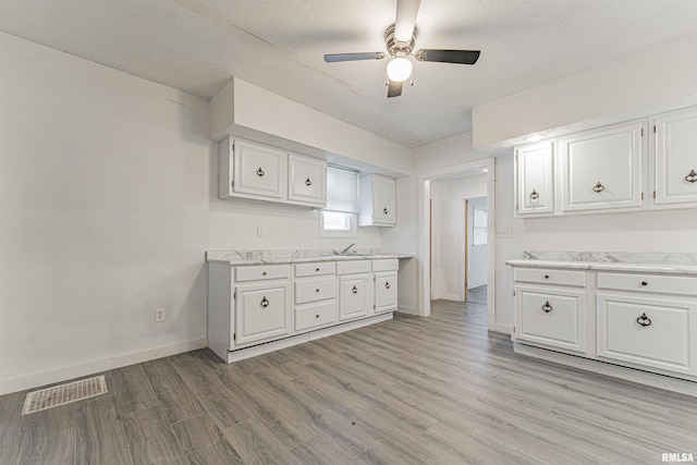 kitchen with ceiling fan, white cabinetry, light hardwood / wood-style flooring, and sink