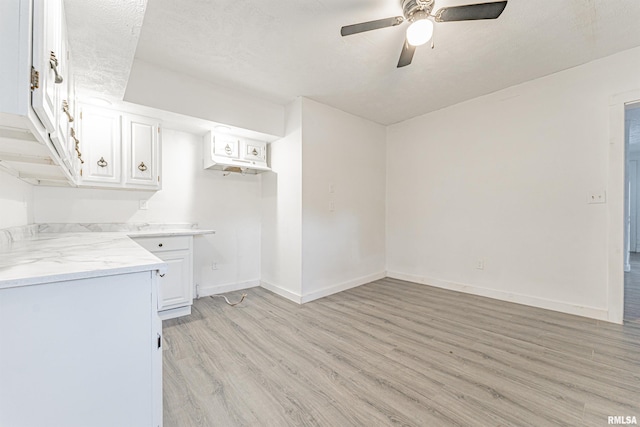 kitchen featuring ceiling fan, light stone counters, white cabinetry, and light hardwood / wood-style floors