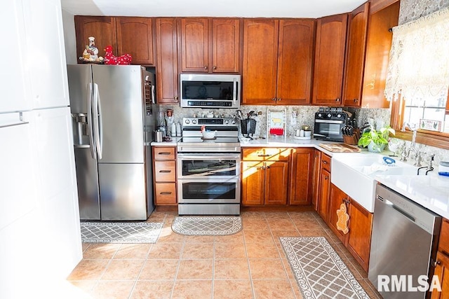 kitchen featuring light tile patterned floors, decorative backsplash, appliances with stainless steel finishes, and sink