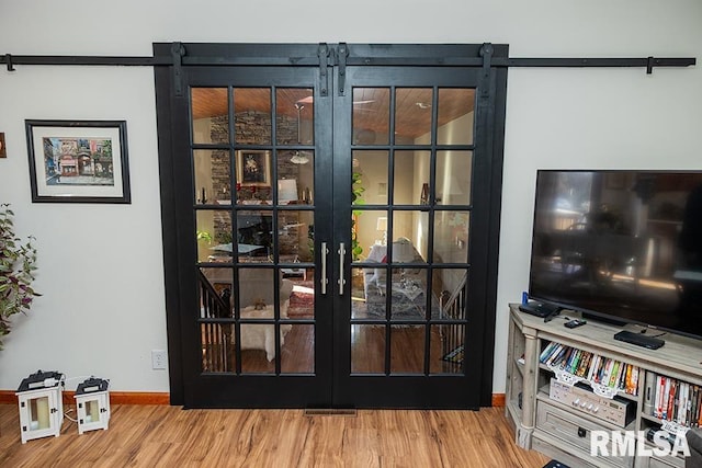 doorway with french doors, wood-type flooring, and a barn door