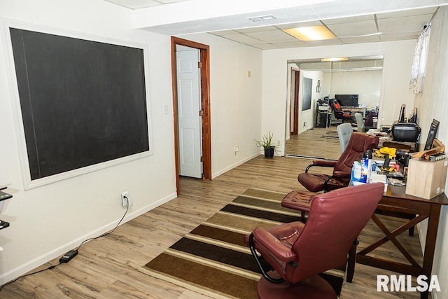 interior space featuring a paneled ceiling and light hardwood / wood-style flooring