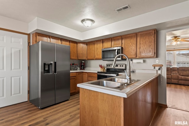 kitchen featuring ceiling fan, kitchen peninsula, stainless steel appliances, a textured ceiling, and light hardwood / wood-style flooring