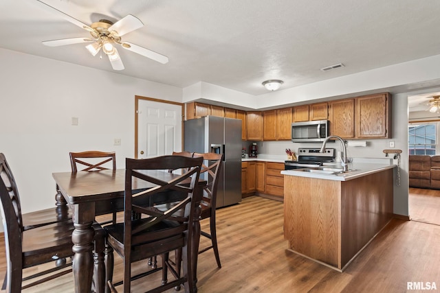 kitchen featuring sink, light wood-type flooring, appliances with stainless steel finishes, kitchen peninsula, and ceiling fan