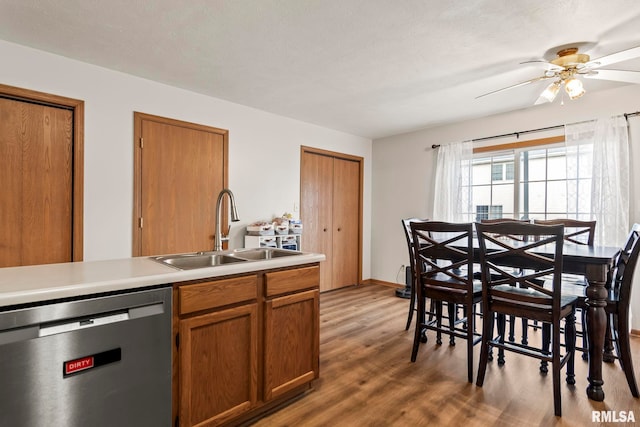 kitchen with dishwashing machine, sink, hardwood / wood-style flooring, ceiling fan, and a textured ceiling