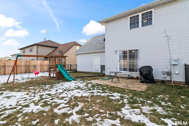 snow covered playground featuring a yard and a patio area