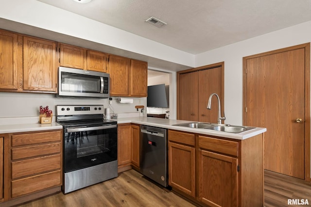 kitchen featuring appliances with stainless steel finishes, sink, dark hardwood / wood-style floors, and kitchen peninsula