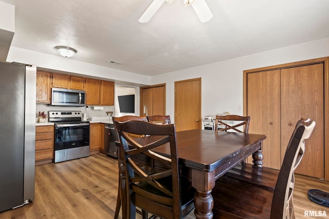 dining area with wood-type flooring and ceiling fan