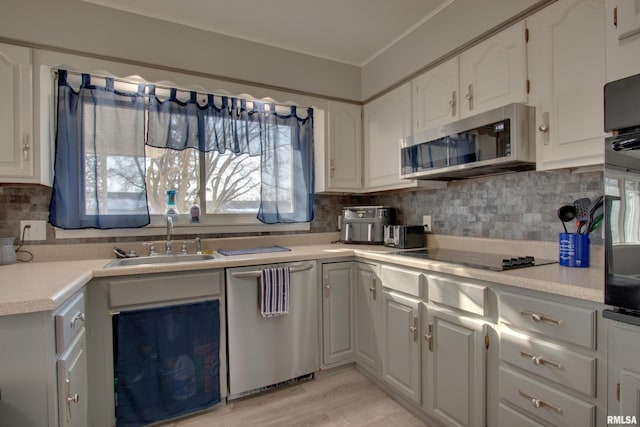 kitchen featuring white cabinetry, backsplash, light wood-type flooring, black appliances, and sink