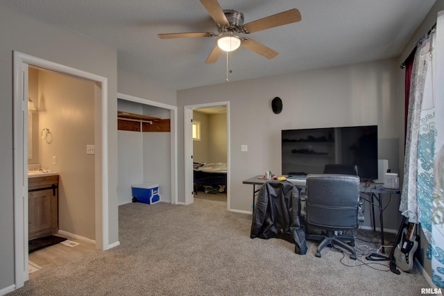 office featuring ceiling fan, light colored carpet, and a textured ceiling