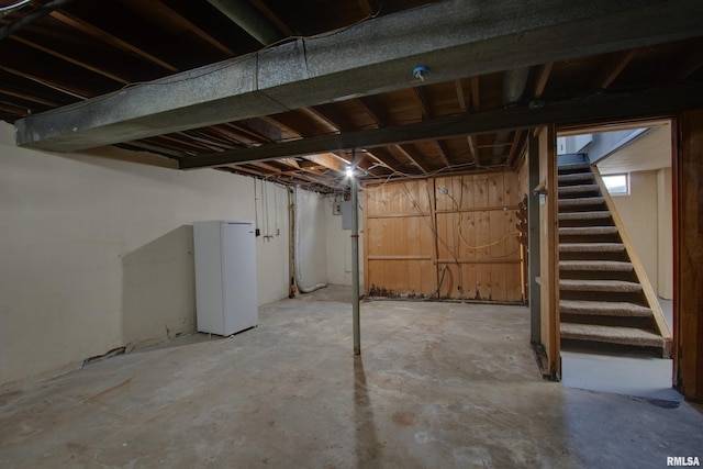 basement with electric panel and white refrigerator