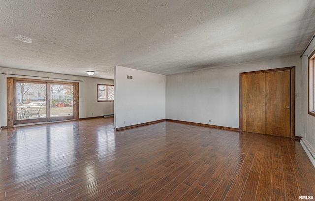 spare room with a textured ceiling and dark hardwood / wood-style floors