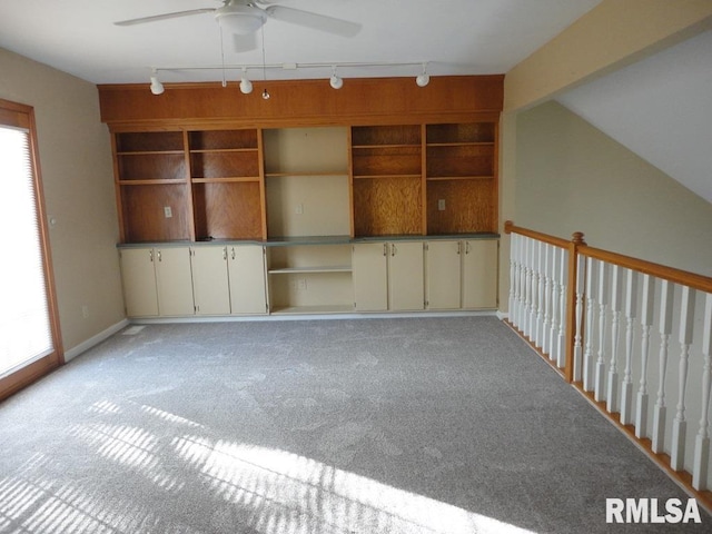 empty room with built in features, ceiling fan, light colored carpet, and plenty of natural light