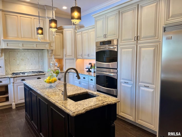 kitchen with light stone counters, stainless steel appliances, a kitchen island with sink, and sink