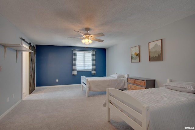 carpeted bedroom with ceiling fan, a barn door, and a textured ceiling