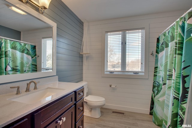 bathroom with hardwood / wood-style flooring, vanity, wooden walls, and toilet