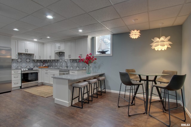 kitchen with white cabinetry, pendant lighting, stainless steel appliances, and a kitchen breakfast bar