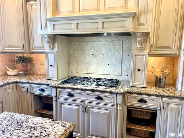 kitchen featuring tasteful backsplash, light stone countertops, stainless steel gas stovetop, and premium range hood