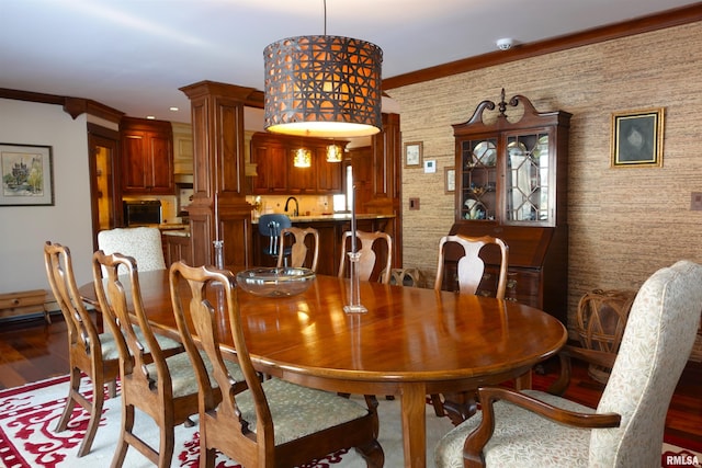 dining area with crown molding, hardwood / wood-style floors, sink, and decorative columns