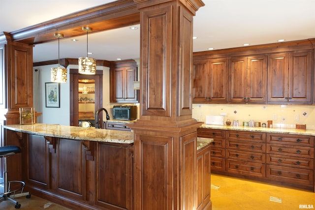 kitchen with decorative light fixtures, a kitchen breakfast bar, light stone counters, and crown molding