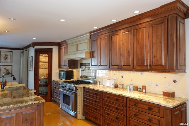 kitchen with sink, backsplash, high end range, and light stone countertops