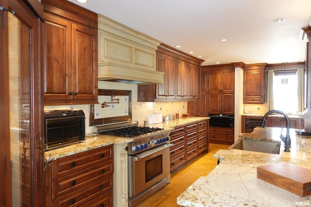 kitchen with sink, light stone counters, high end stove, and tasteful backsplash