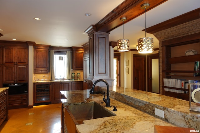 kitchen featuring decorative light fixtures, sink, beverage cooler, and light stone countertops