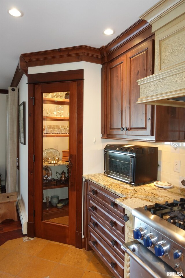 kitchen with light stone counters, backsplash, a baseboard heating unit, and ornamental molding