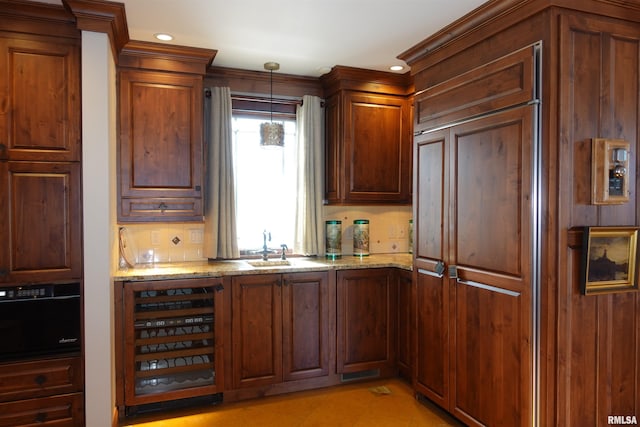 kitchen featuring light stone countertops, hanging light fixtures, wine cooler, and sink