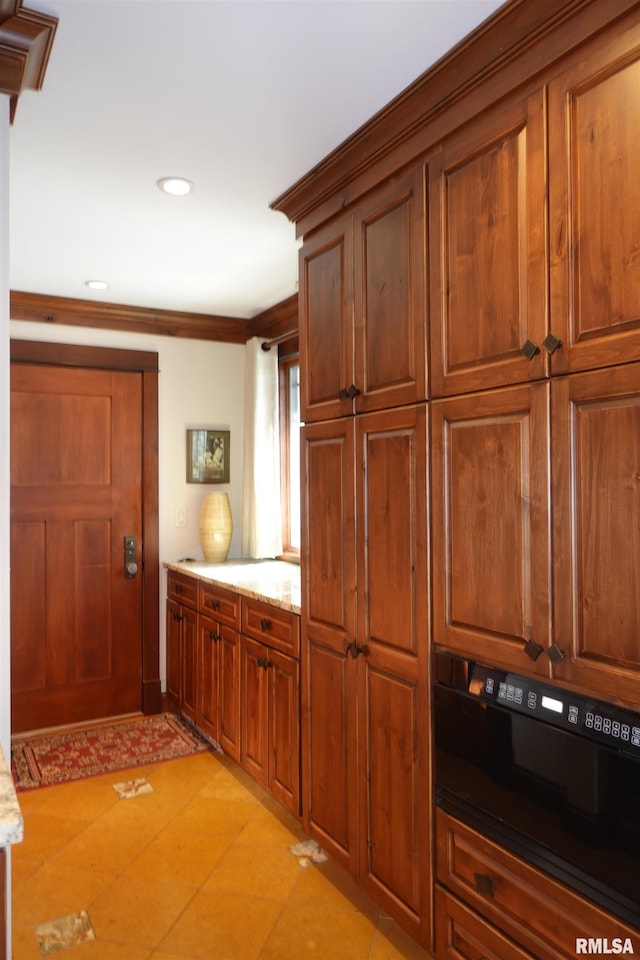 kitchen with crown molding, light tile patterned floors, and light stone countertops