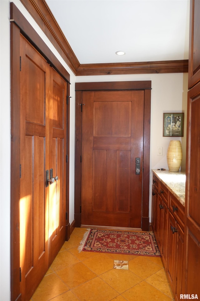 doorway with crown molding and light tile patterned floors