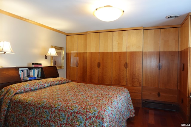 bedroom with dark hardwood / wood-style flooring, two closets, and ornamental molding