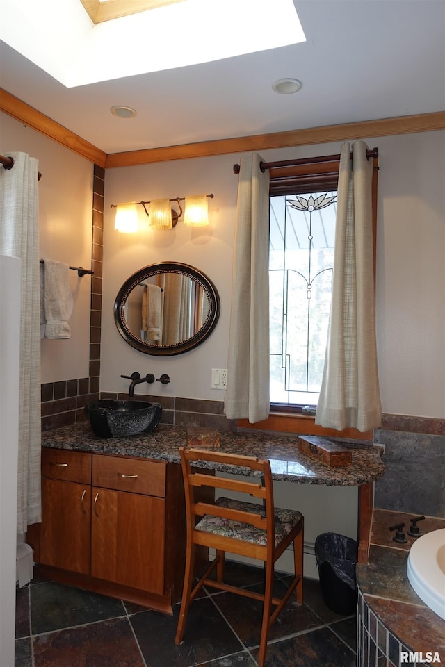 bathroom with vanity, a skylight, ornamental molding, and a bathtub