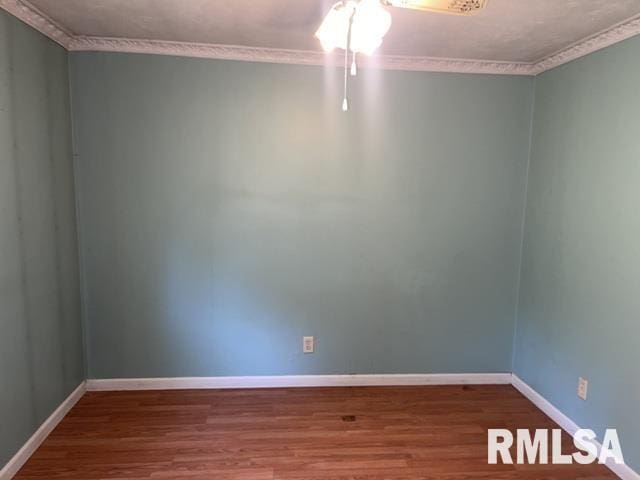 empty room with hardwood / wood-style flooring and crown molding