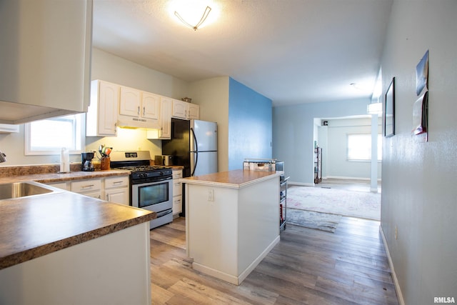 kitchen with a center island, white cabinetry, sink, light wood-type flooring, and stainless steel appliances