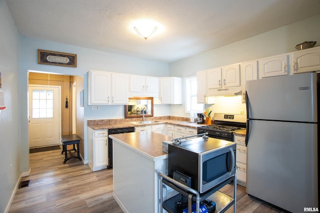 kitchen with sink, a kitchen island, white cabinetry, and appliances with stainless steel finishes