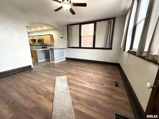 unfurnished living room featuring ceiling fan and dark hardwood / wood-style flooring