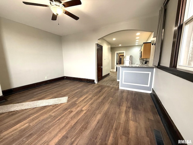 unfurnished living room featuring ceiling fan and dark hardwood / wood-style flooring