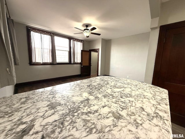 unfurnished bedroom with ceiling fan and dark wood-type flooring