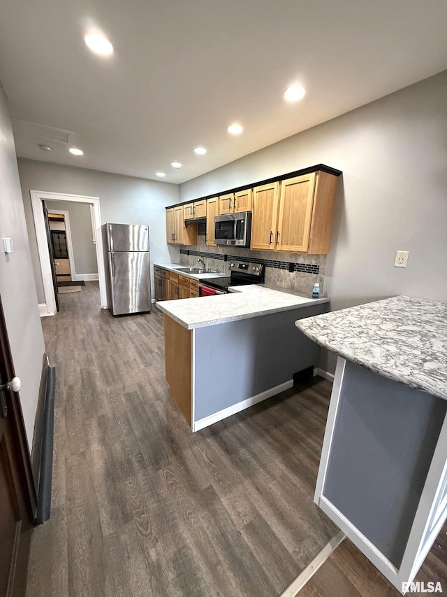 kitchen with kitchen peninsula, dark hardwood / wood-style flooring, sink, backsplash, and stainless steel appliances