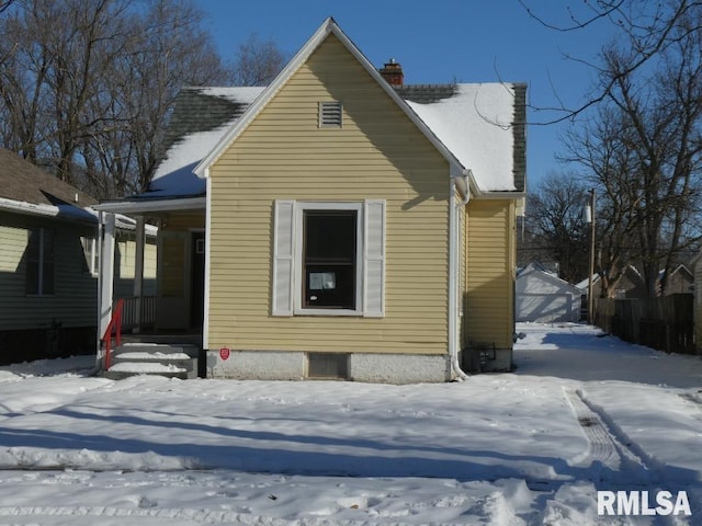 snow covered back of property featuring covered porch