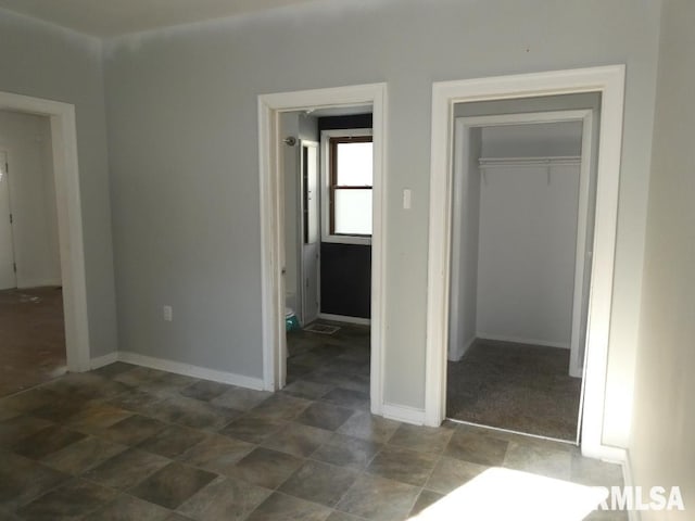 unfurnished bedroom featuring a closet and dark carpet