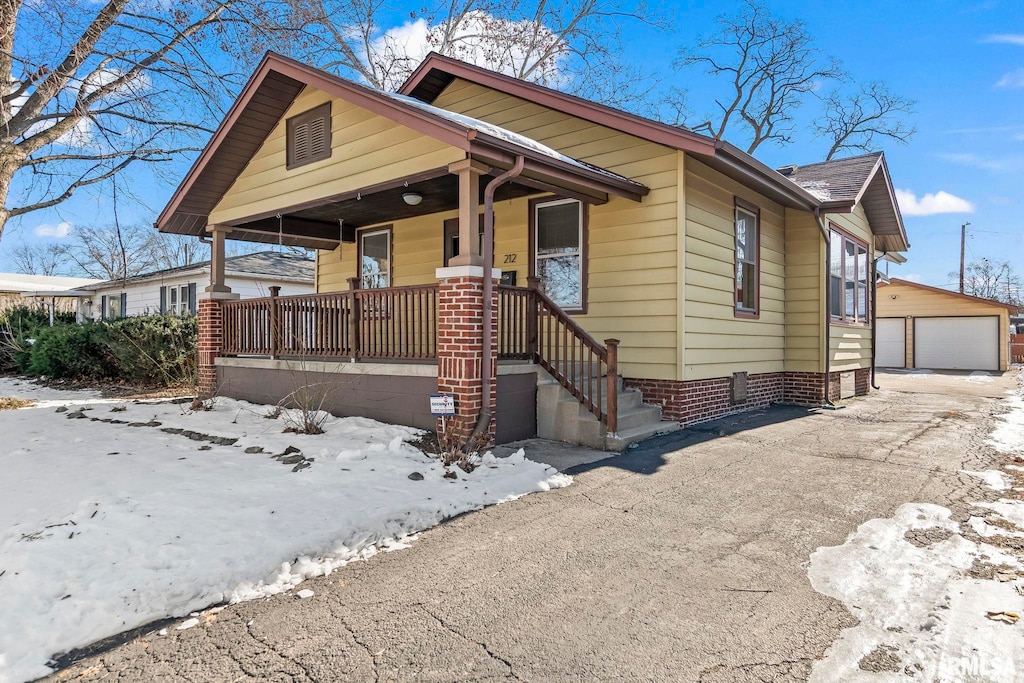 bungalow featuring a garage, an outdoor structure, and a porch