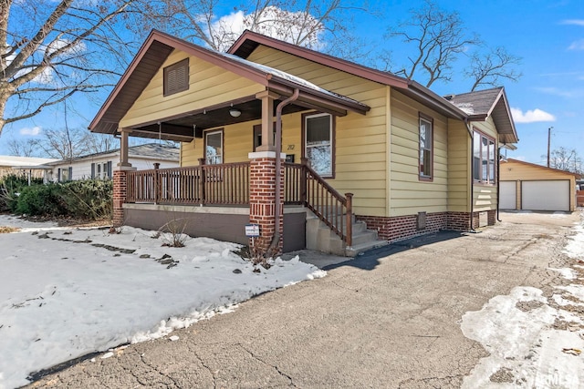 bungalow featuring a garage, an outdoor structure, and a porch